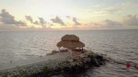 aerial - a cabana in rocky pier at sunrise, cancun, mexico, wide spinning shot