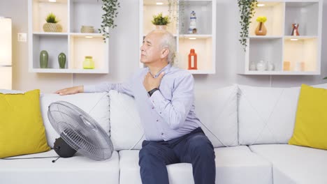 el viejo se enfría con un ventilador debido a la temperatura del aire.