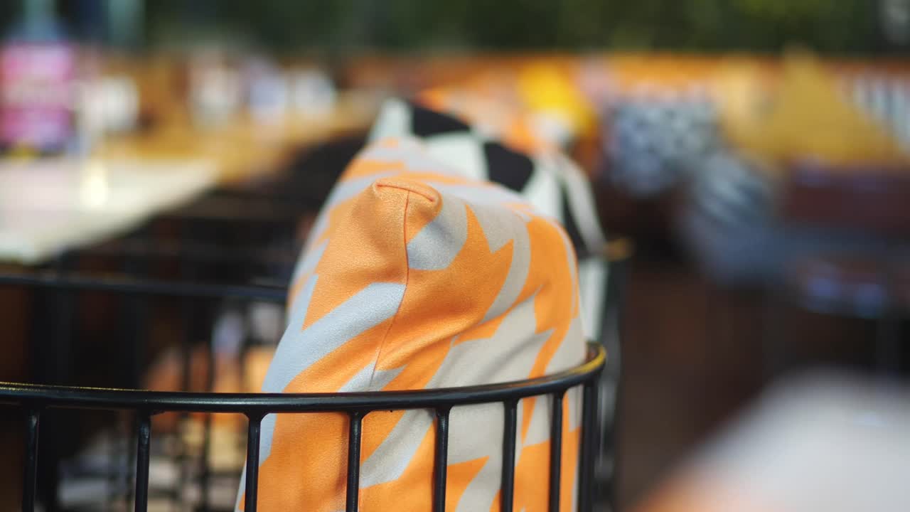 Close-up of a Modern Chair with Orange Patterned Cushion in a Cafe