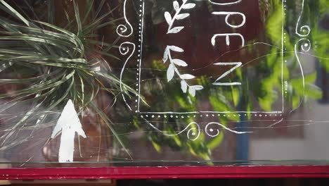 open sign on a shop window with plants