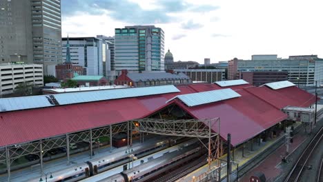 train station with red roofs, trains, and surrounding urban skyline