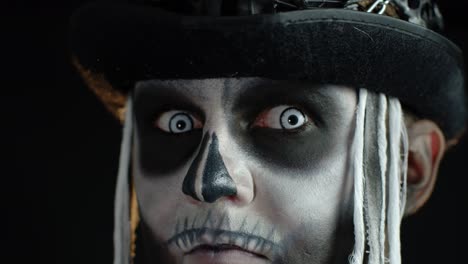 Close-up-of-scary-man-face-in-carnival-skull-Halloween-makeup-of-skeleton-looking-creepy-at-camera