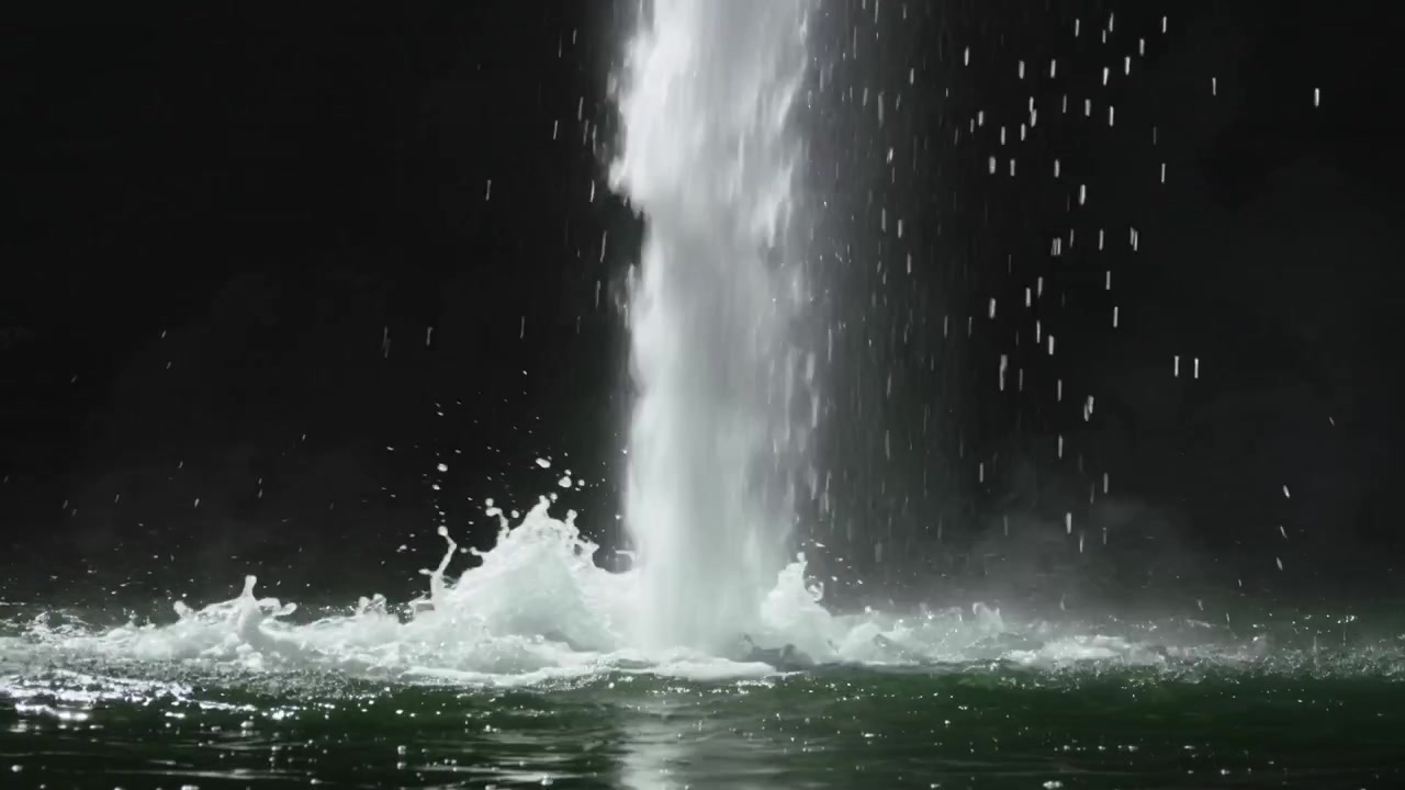 印象的な垂直の水柱が泡の冠を形成し、暗い緑のプールに落ちる水滴がエネルギーを放散する。