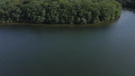 Aerial-drone-ascending-pov-over-Trémelin-or-Tremelin-over-lake-and-green-lush-forest,-Brittany-in-France