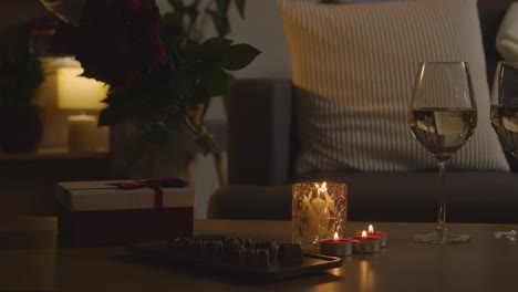 man planning romantic evening at home in lounge with wine chocolates gift and roses