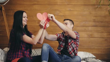 enamored man and woman are playing with cut out hearts of red color on the bed on the eve of saint valentine