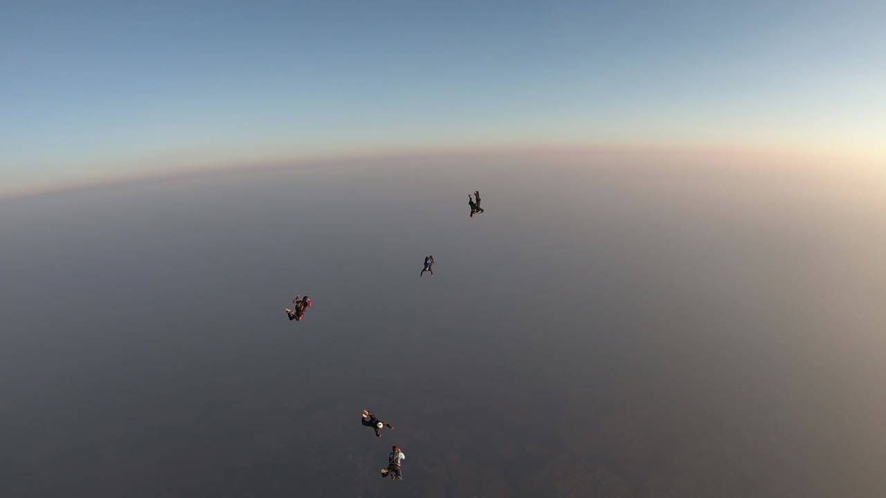 하루가 끝날 무렵 점프하는 스카이 다이버 그룹의 실루입니다.
