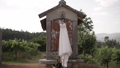 el vestido de novia cuelga de un espigueiro de piedra tradicional, con viñedos exuberantes en el fondo