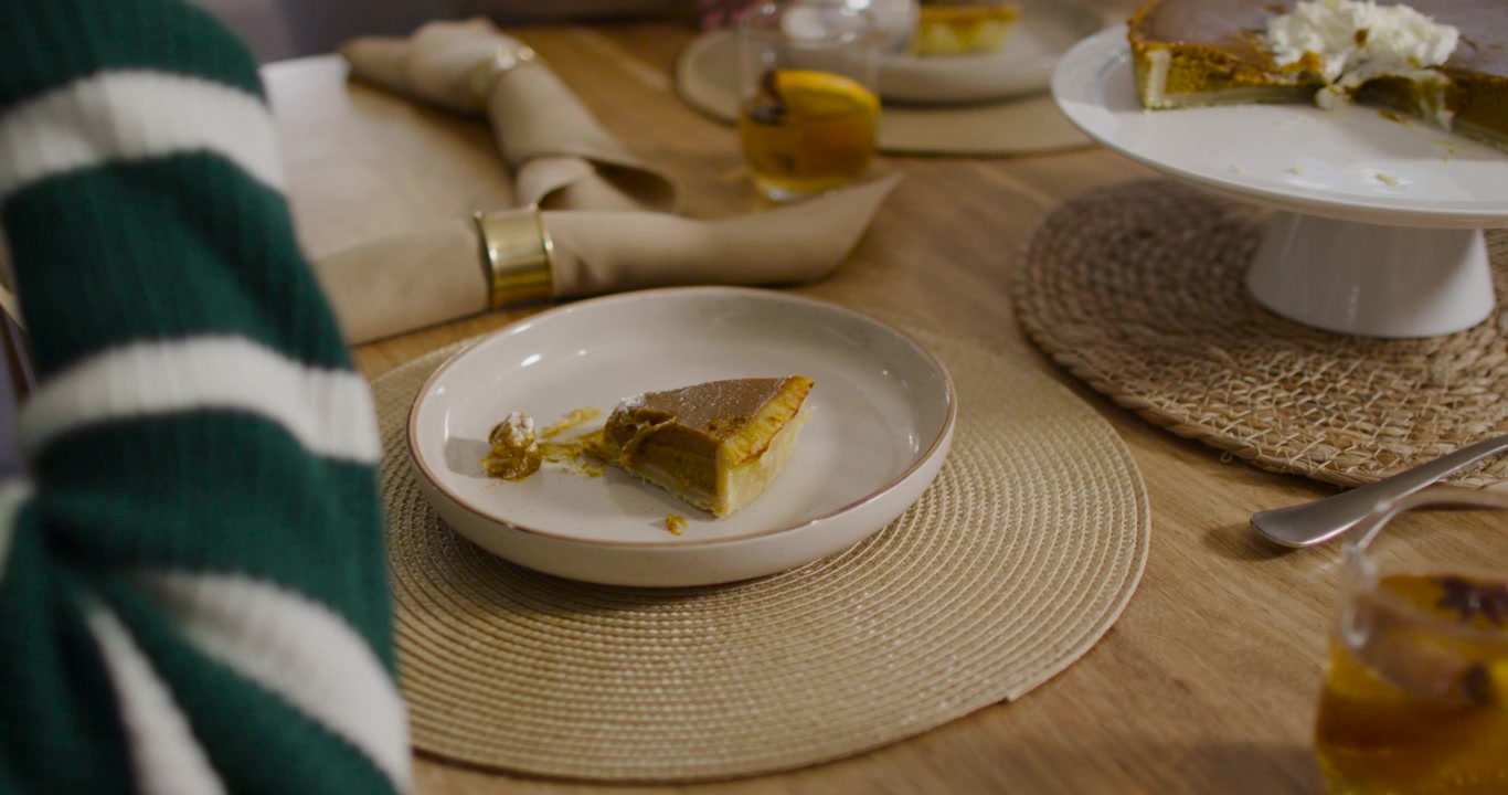 Mujer afroamericana acercando una cuchara a un soporte para pasteles, cubriendo una porción de tarta en la mesa, con espacio para texto.