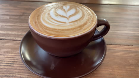 Un-Café-Con-Leche-Sobre-Una-Mesa-De-Madera-En-Una-Cafetería