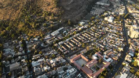 Carretilla-Aérea-En-Los-Edificios-Del-Barrio-De-La-Ciudad-De-Santiago-Cerca-De-La-Ladera-De-San-Cristobal-A-La-Hora-Dorada,-Chile