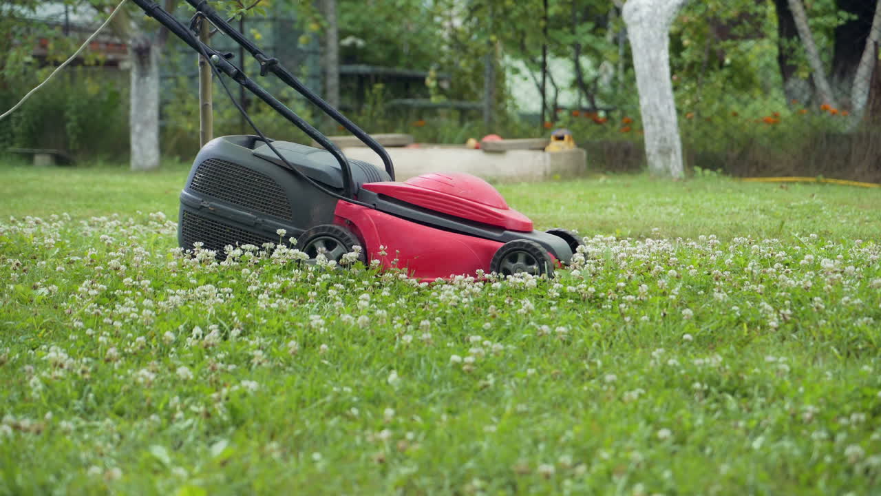 Boy running with a lawn mower in the garden. Close-up