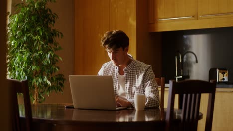 man working on a laptop in a kitchen