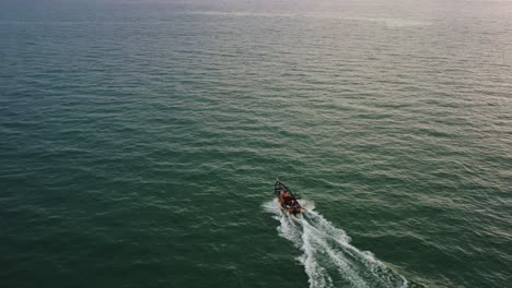 toma aérea de drones capturando un pequeño barco de pesca tradicional navegando en el mar al atardecer