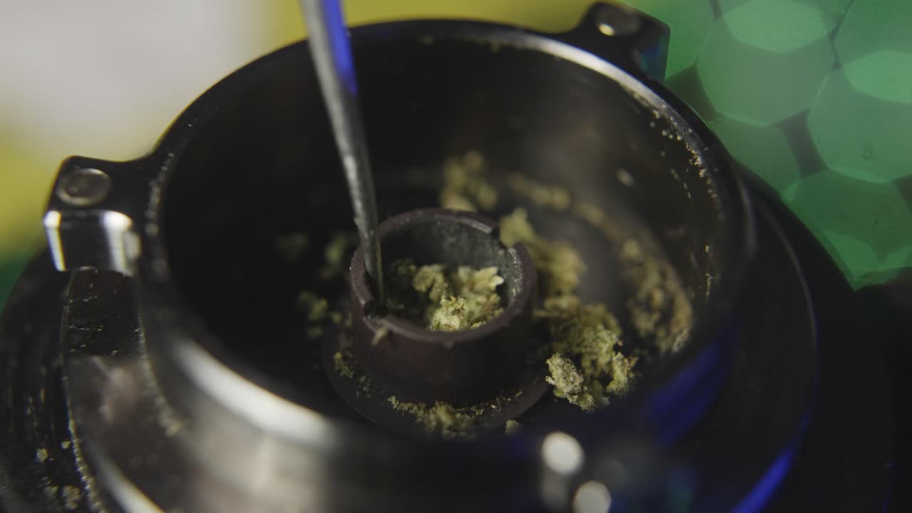 Usando uno stilo per sistemare il fiore di cannabis nel braciere di un vaporizzatore elettronico
