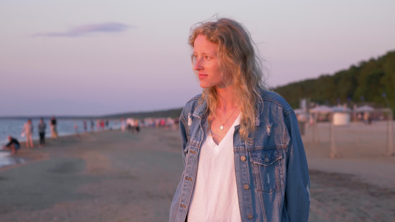Afslappet kvinde står på stranden og venter på, at hendes venner kommer.
