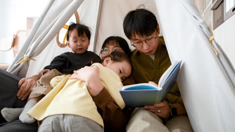 family reading together in a play tent