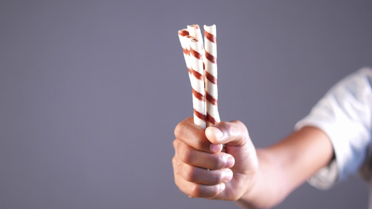 Mano che tiene bastoncini di wafer ricoperti di cioccolato