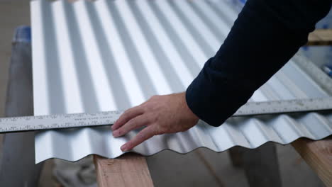 a construction worker measuring sheet metal with a straight edge ruler before cutting