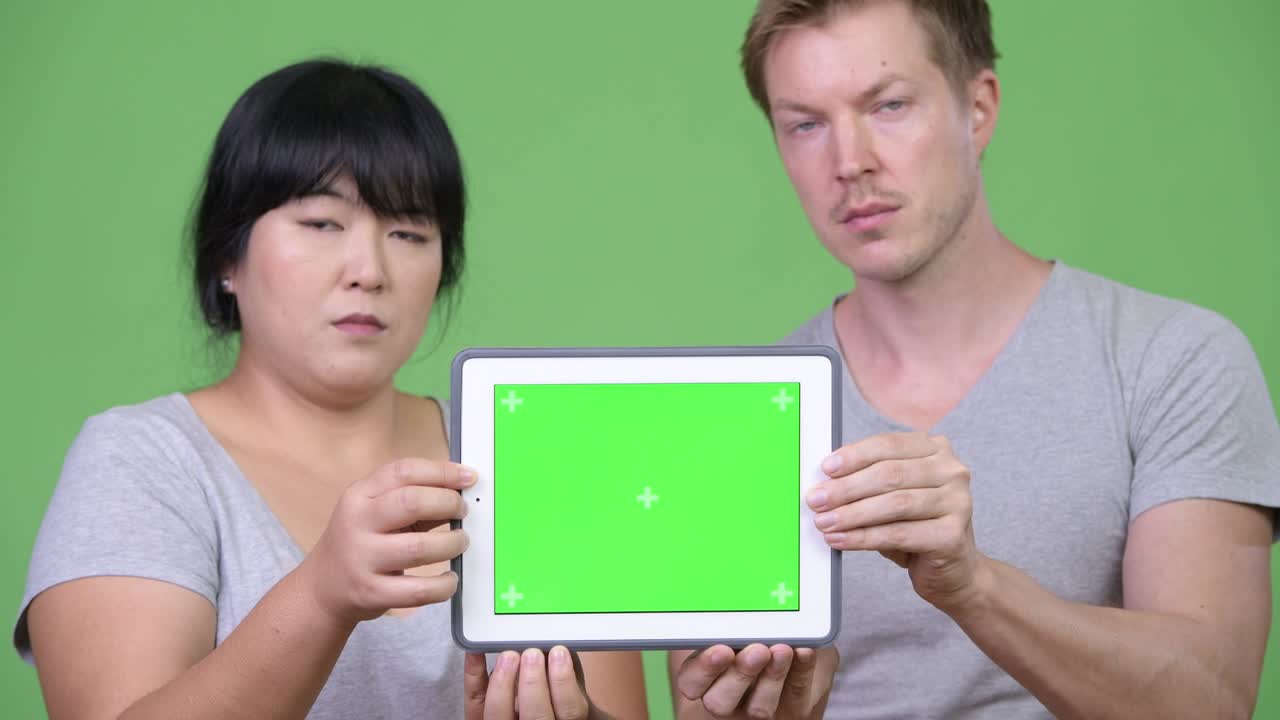 Young happy multi-ethnic couple showing digital tablet together