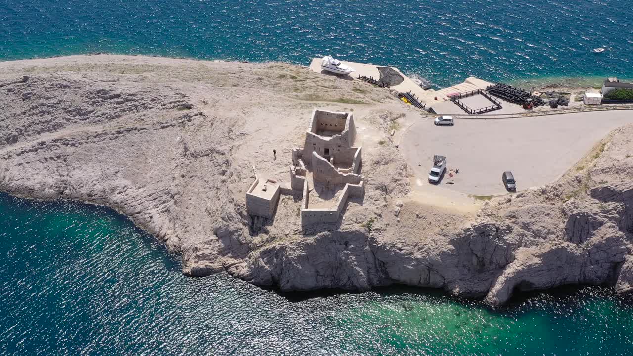 Ruine Fortica Fort in Pag Island Croatia used to defend from pirates on the shipping route with cars parked nearby, Aerial dolly in shot
