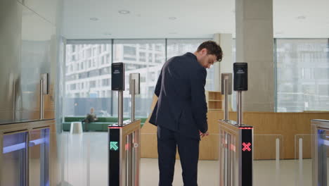 man leaving office turnstile trying unlocking security system by smartwatch.