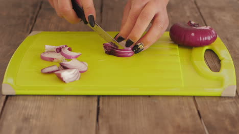 mujeres picando cebollas rojas en una tabla de cortar en la cocina