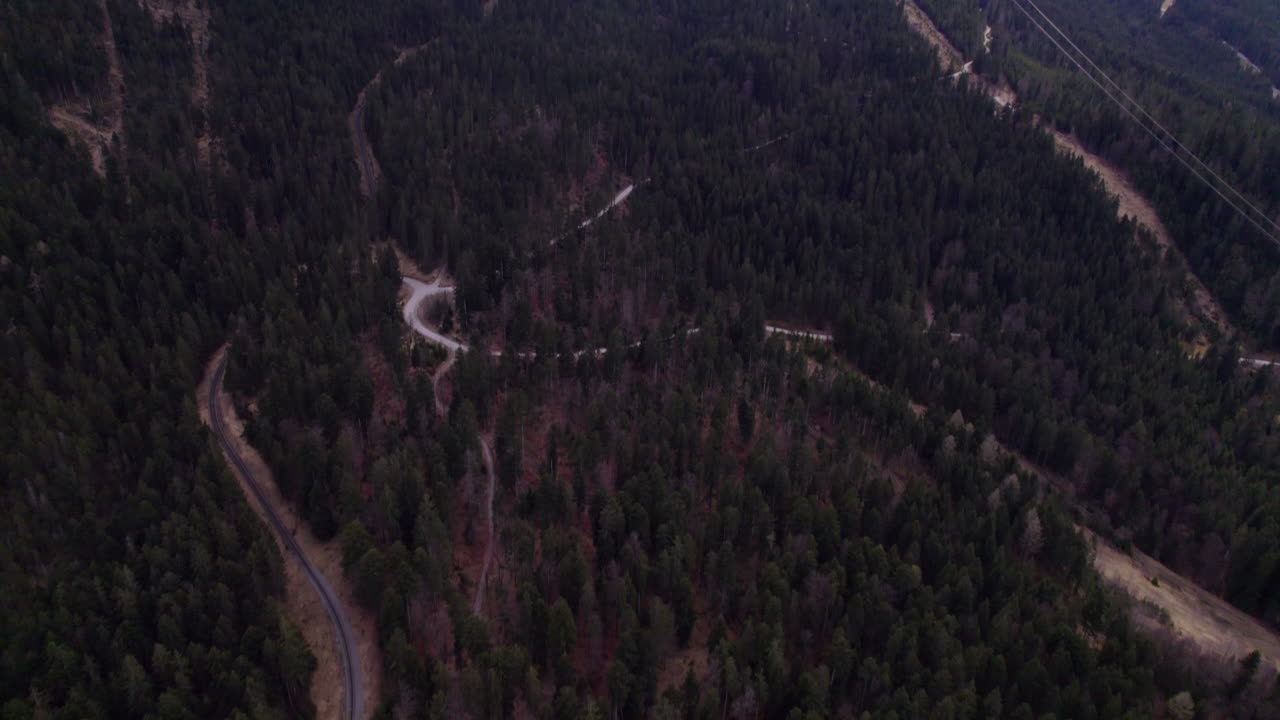 High Quality aerial view of the Zugspitze with snow covered peaks dense forest below and the cable car gliding up the mountain suspended in bright alpine light atmosphere steady and calm
