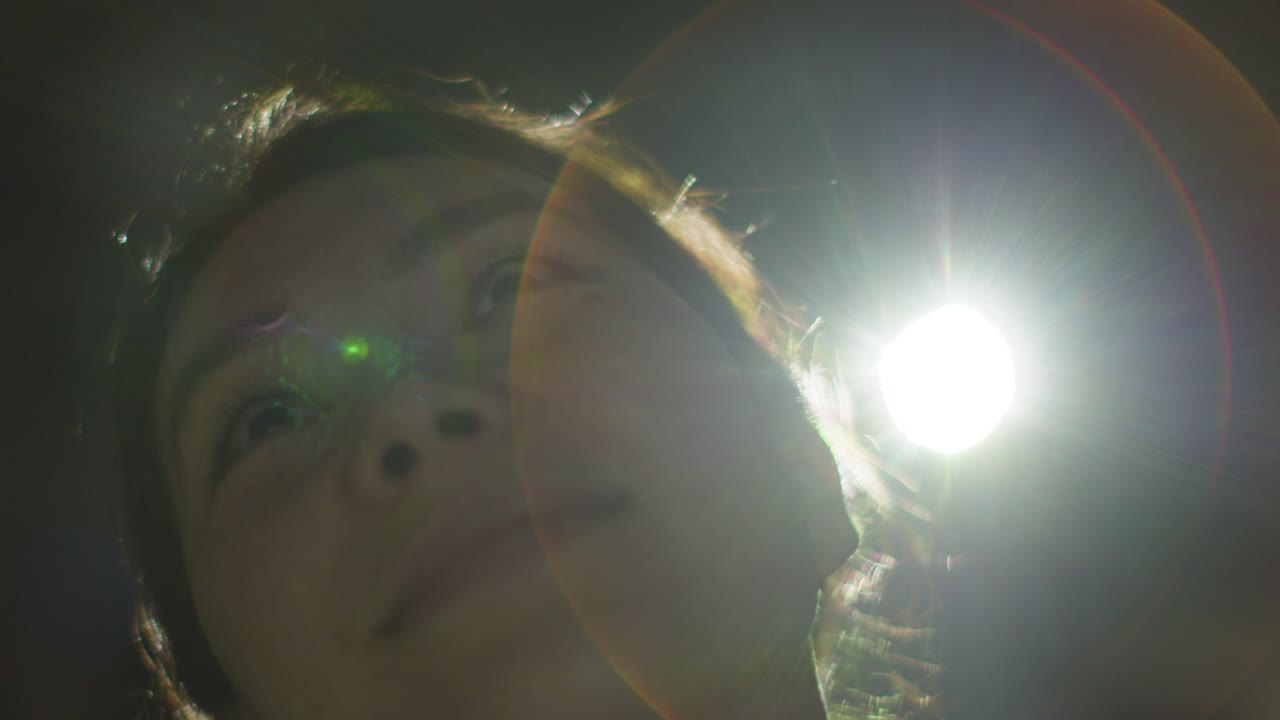 프로젝터 2의 빛에 의해 백라이트 된 몰입 예술 전시회를 방문하고 상호 작용하는 여성의 클로즈업