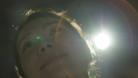 primer plano de una mujer que visita e interactúa con una exposición de arte inmersiva retroiluminada por la luz del proyector 2