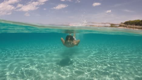 Young-little-girl-swims-beneath-sea-water-surface-of-Saleccia-exotic-beach-in-Corsica-island,-France