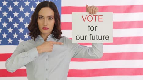 woman holds "vote for our future" sign in front of us flag