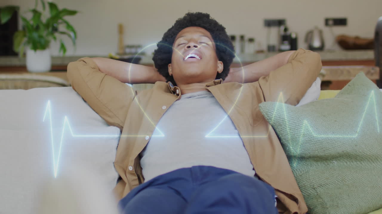 Un homme allongé sur un canapé dans un salon moderne, affichant l'icône de cœur d'une application de santé avec une ligne ECG.