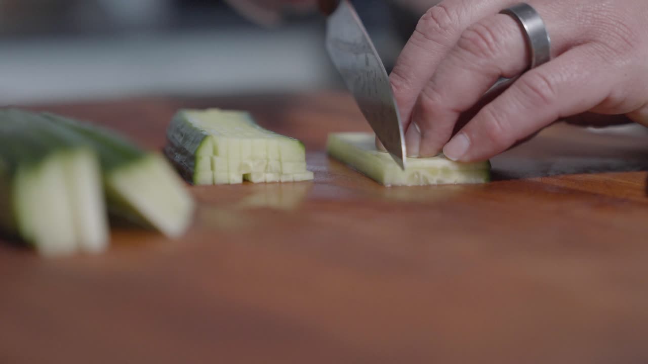 Close-up shot of a chef slicing cucumbers into tiny squares, showcasing precision and technique. Perfect for cooking tutorials, food preparation, and culinary presentations.