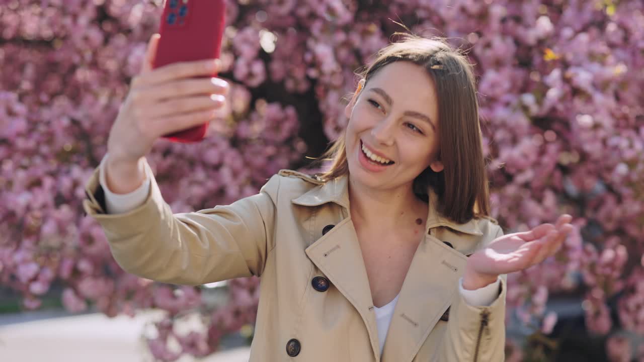 Mujer tomándose una selfie en un parque con cerezos en flor