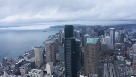 wide aerial shot pulling away from seattle's looming skyscrapers on a wet and cloudy day