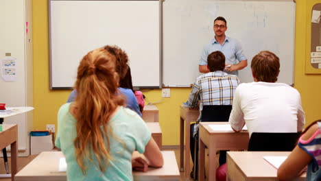 Lecturer-writing-on-the-whiteboard-then-turning-and-speaking-to-class