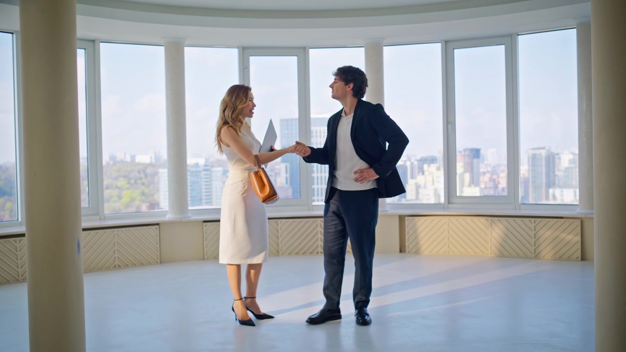Agente immobiliare stringe la mano all'acquirente in un appartamento di lusso. Affare immobiliare di successo con vista sulla città.