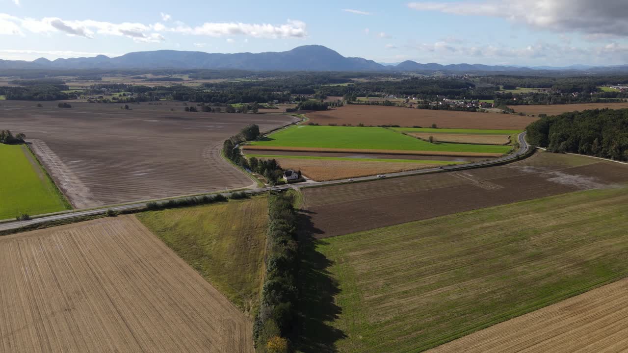 día soleado y una carretera en medio de los campos con colinas al fondo -- drone