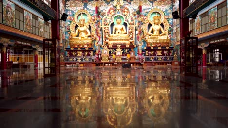 a dramatic scene of the tibetan monastery interiors where large statues of buddhas in different forms decorated with golden color at bylakuppe town in karnataka, india.