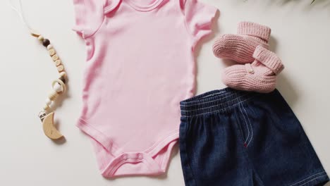 video of close up of pink baby grow, socks and skirt on white background