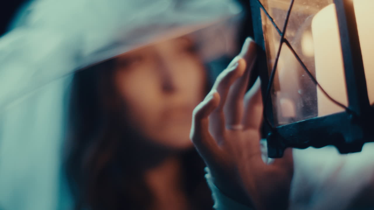 A woman holding a lantern under a veil