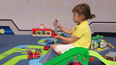 little girl playing with toy cars sitting on a floor at home