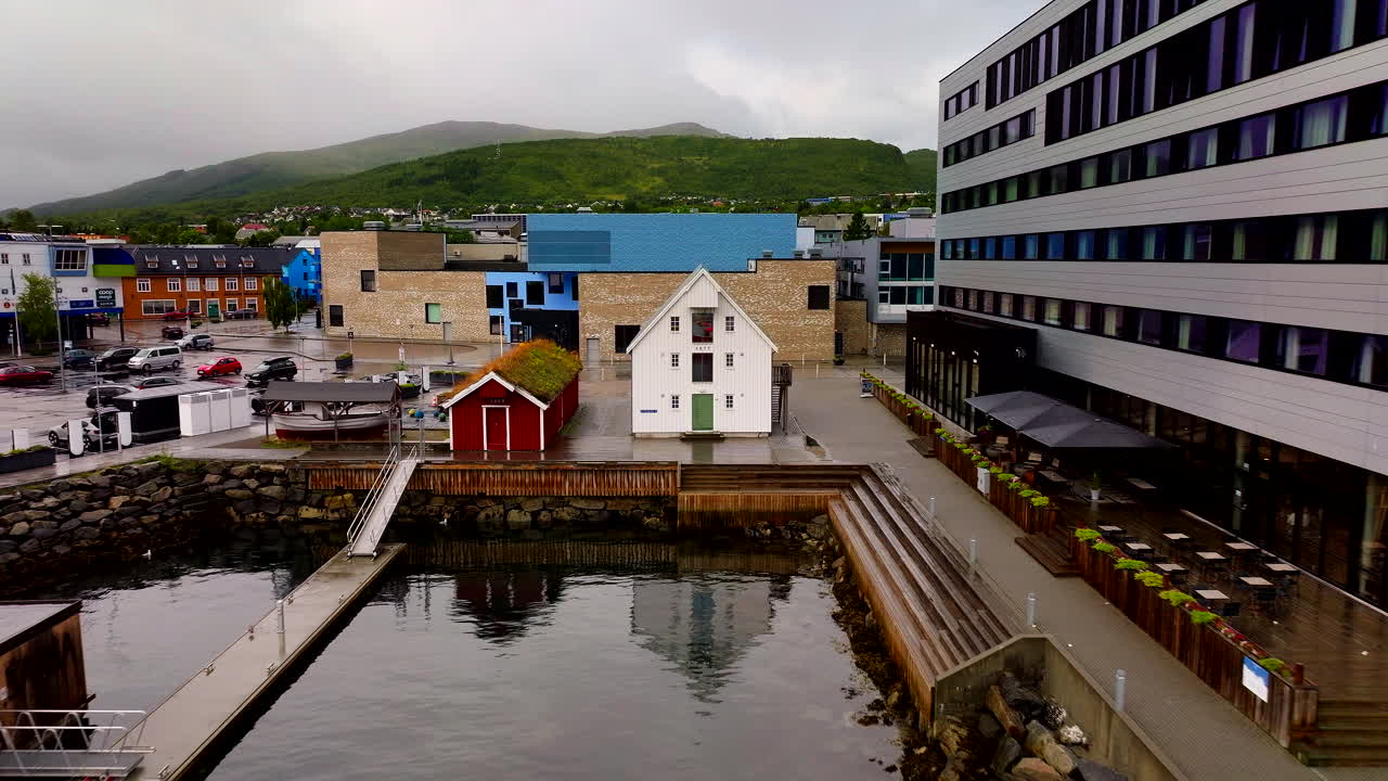 Moderne Gebäude an der Uferpromenade säumen den Hafen mit Bergen, die sich hinter der Stadt erheben, in Sortland in Vesterålen, Nordnorwegen – Luftaufnahme