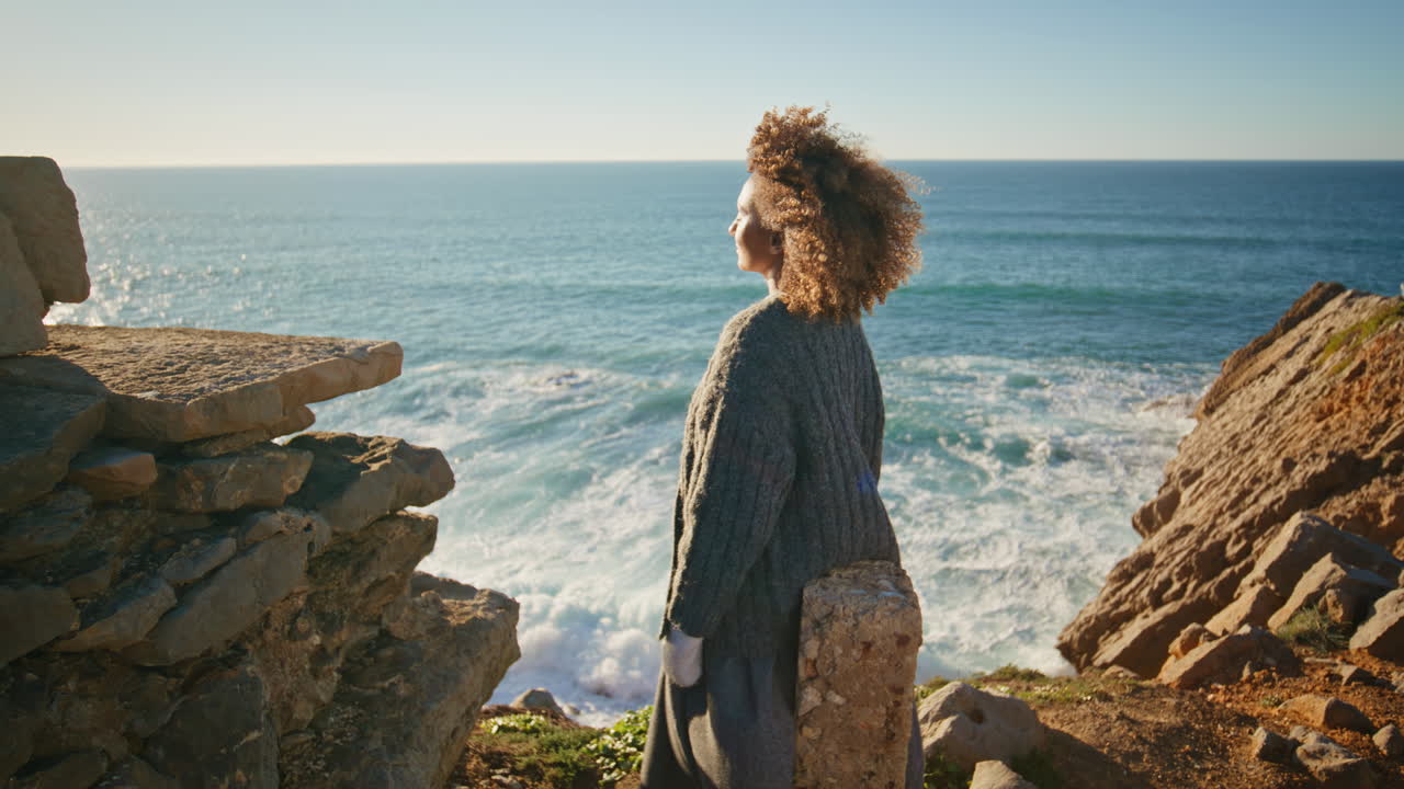 Curly woman contemplating ocean at windy coast zoom on. Girl watching sea nature