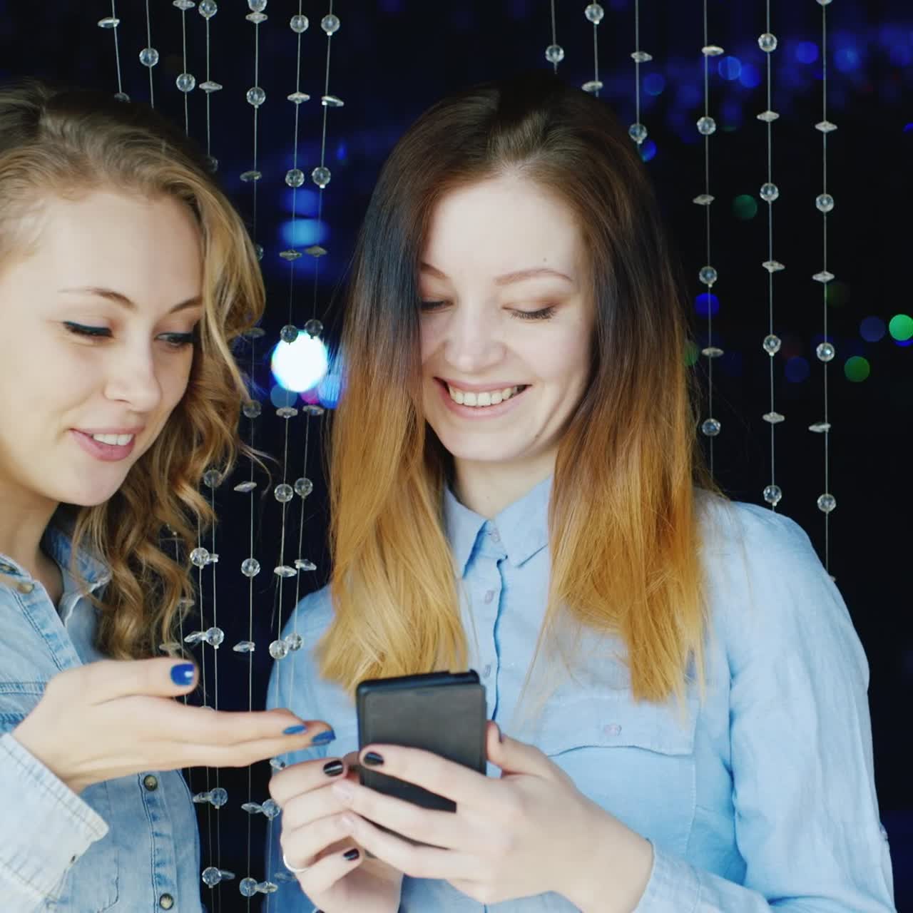 dos mujeres jóvenes usan un teléfono inteligente y se divierten
