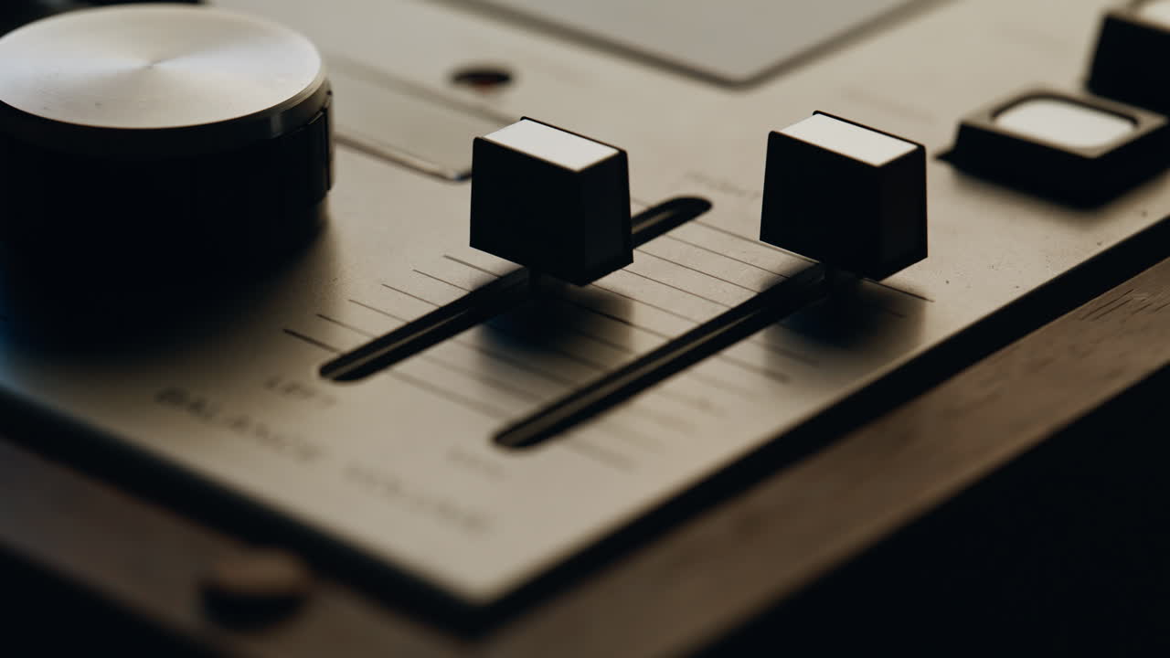 Closeup hand balancing volume on vintage digital audio mixer. Unknown man fader