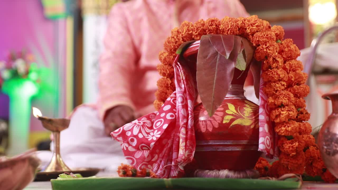 Close-up shot of a lamp lightened and pot with flowers during the Indian wedding ceremony.