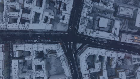 Aerial-birds-eye-overhead-top-down-descending-view-tram-and-road-vehicles-passing-through-crossroad.-Thin-layer-of-snow-in-city.-Berlin,-Germany