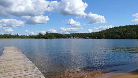 beautiful canadian lake pan - cottage wooden dock with pine trees and fluffy clouds on horizon